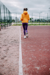 Fototapeta premium Woman doing sport on the court. Woman is running in headphones.