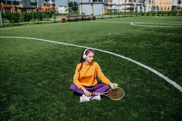Obraz premium Woman playing on the tennis court. Woman holding tennis racket and ball on the green grass.