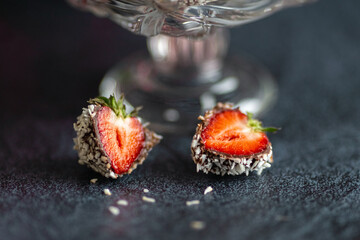 Chocolate covered strawberries. Covered with coconut flakes. on a dark background. decor for strawberries. Delicious delicacy. A treat for the holiday.