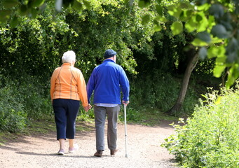 elderly couple holding hands and walking