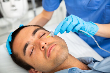 Male client getting carbon dioxide injections for face skin rejuvenation in clinic of aesthetic...