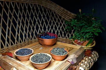 still life on a wicker sofa with dry tea leaves and fresh berries in ceramic cups