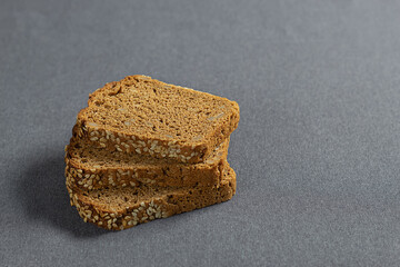 Slices of bread with seeds and sesame seeds on a gray background. Side view