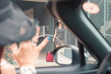 Elegant woman in mini dress walking towards the car with suitcase
