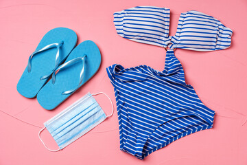 Obraz premium Coronavirus summer. Blue bikini with flip-flops and protective mask