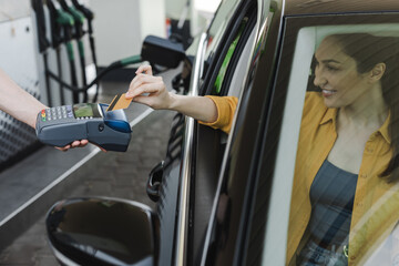 Naklejka premium Selective focus of worker of gas station holding payment terminal near smiling woman paying with credit card in car