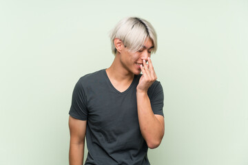 Young asian man over isolated green background smiling a lot