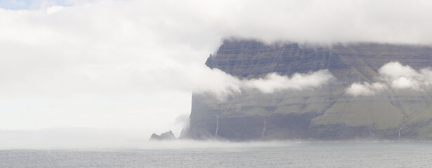 Fototapeta na wymiar Steep mountain cliffs next to the ocean on Kalsoy Island in the Faroe Islands, Denmark.