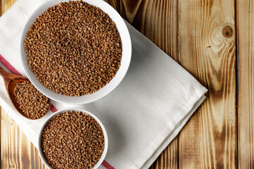 Bowl of raw uncooked buckwheat on wooden table