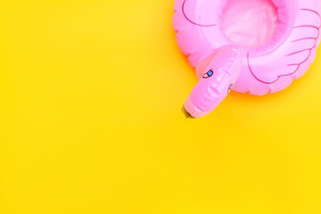 Summer beach composition. Simply minimal design with pink Inflatable flamingo isolated on yellow background. Pool float party, trendy celebrity fashion concept. Flat lay top view copy space.