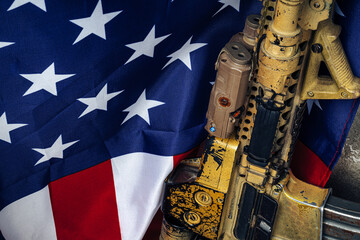U.S. battle flag and assault rifle near the wall. close up.