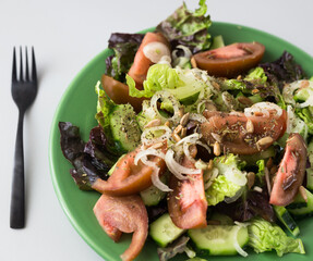 vegetable salad of greens, tomatoes and cucumbers on a green plate