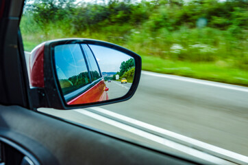 Fototapeta na wymiar Reflection of blurred cars in the rear view mirror on highway
