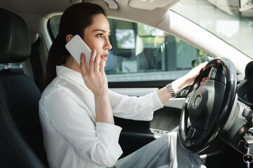 Side view of beautiful businesswoman talking on smartphone while driving car