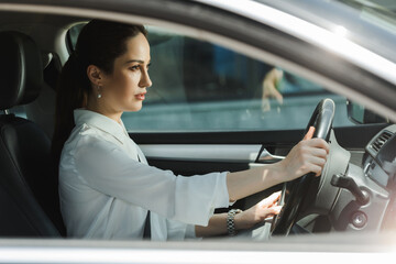 Fototapeta na wymiar Side view of attractive businesswoman driving car