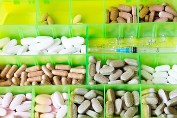 Plastic box with cells for pills close-up. The treatment schedule for the days of the week with pills for the disease - 365012537