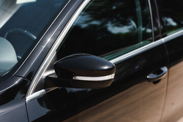 Selective focus of long range mirror on black car outdoors