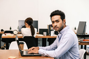 Fototapeta premium An Asian teenage man is sitting on a desk with a notebook. He is a company manager. he works hard to make the company successful.