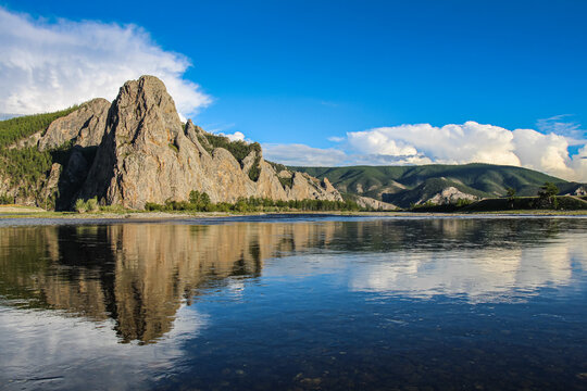 A Mongolian mountain reflecting on the Delger Murun River, in the evening sun