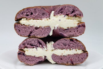 Cut in Half Blueberry Bagel with Cream Cheese on a White Plate with a White Background
