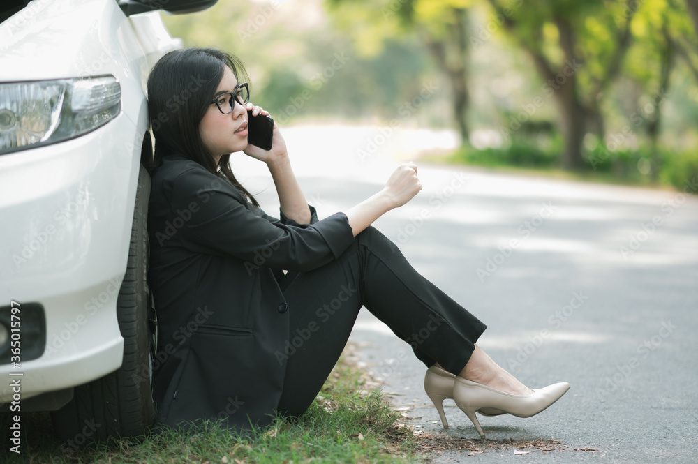 Wall mural a young asian woman is calling her service technician to fix a broken car on the side of the road