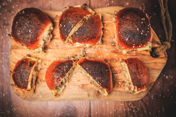 Homemade beef burger with cheese sliced in half with other burgers on the side on a wooden board with free space for text/decoration. Interior view of the burger.