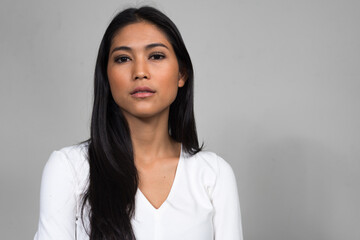 Portrait of young beautiful Asian woman against white background