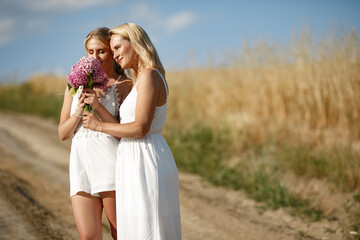 Adult mother with daughter. Beautiful girl in a white dress. Family in a summer field