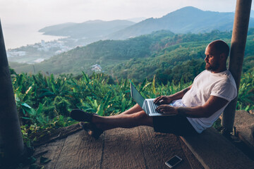 Young caucasian man freelancer working remote on laptop computer while enjoying nature landscape...