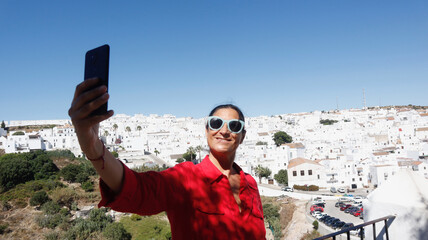 Mature beautiful woman tourist taking photos and selfies with her celular in Vejer de la Frontera, Cadiz, Andalusia, Spain
