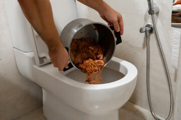 The girl pours a pot of soup into the toilet. Spoiled food