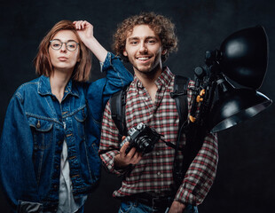 Portrait of a attractive young couple - Handsome photographer and beautiful fashionable model posing in dark studio