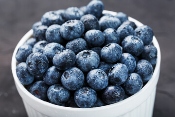 Organic blueberries in a white Cup on a black Board.