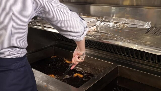Frying and scooping fish called Kibbeling in the fryer of a restaurant