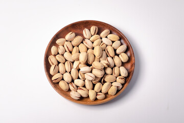 Baked Pistachios in a wooden plate on a white background