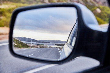 Car Mirror and reflection of the road and sky in it.