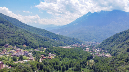 Infrastructure of a modern city in mountains. Aerial view against the background of mountains and peaks. Krasnaya Polyana, Sochi, Russia.