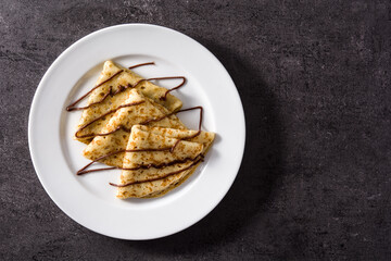 Sweet crepes with chocolate on black background. Top view. Copy space