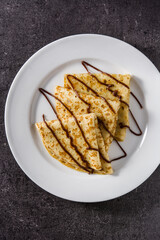 Sweet crepes with chocolate on black background.Top view