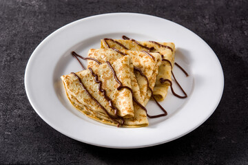 Sweet crepes with chocolate on black background