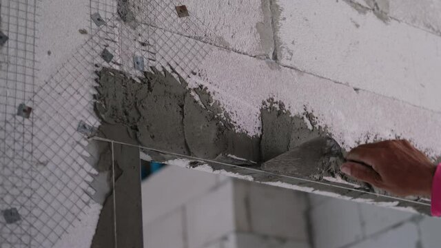 labor worker bricklayer use trowel with liquid cement making coner beads door in house site building