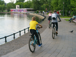 Obraz premium Public park image. Youth biking here. Summer day. Sportive healthy lifestyle. Back / rear view.