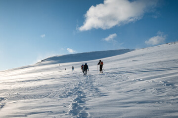 Group of mountaineer climbing on snowy hill and blue sky in winter at Lofoten Islands