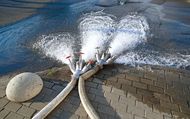 Triple fire hose connection spraying dirty water from central water supply, pour drains into the...