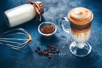Dalgona coffee. Trendy Korean drink creamy whipped coffee with milk on a blue rustic background. Selective focus