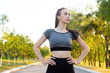 Portrait of sporty athletic woman in sportswear on running road in the park.