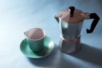 Blue coffee cup and geyser coffee maker stands on a blue background. With copy space.