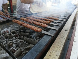 Cooking Adana kebabs on the restaurant style grill