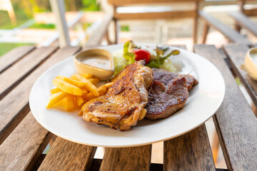 Meat plate of steaks and fries. Chicken and meat on a plate with potatoes in a summer cafe.