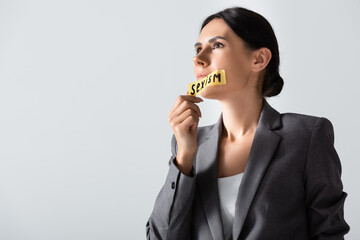 attractive businesswoman taking off scotch tape with sexism lettering on mouth isolated on white